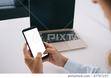 Woman using smartphone and laptop Woman using smartphone and laptop 87767297