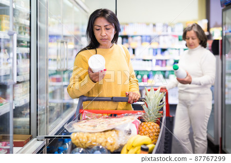 Female shopper chooses dairy products at supermarket Female shopper chooses dairy products at supermarket 87767299
