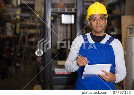Warehouse manager calculates the quantity of goods and writes it down in notebook 87767336