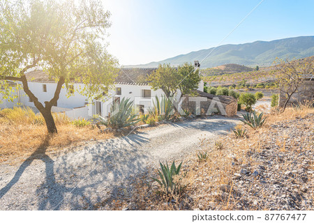 dirt road with hills and mountains and a rural hotel 87767477