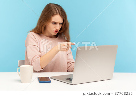 Hey you. Angry businesswoman pointing to laptop screen, scolding and accusing while talking on video call, irritated boss having online conference. indoor studio shot isolated on blue background 87768255