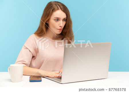 Funny surprised woman employee looking at laptop screen with humorous fish face grimace, talking on video call expressing amazement, online communication. indoor studio shot isolated blue background Funny surprised woman employee looking at laptop screen with humorous fish face grimace, talking on video call expressing amazement, online communication. indoor studio shot isolated blue background 87768378