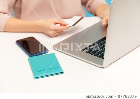 Closeup woman entering credit card and passport data on keyboard laptop, paying for travelling tickets, booking apartment, electronic money transaction and e-commerce. indoor studio shot isolated Closeup woman entering credit card and passport data on keyboard laptop, paying for travelling tickets, booking apartment, electronic money transaction and e-commerce. indoor studio shot isolated 87768379