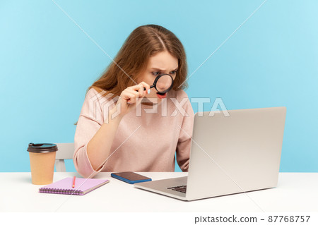 Nosy curious woman journalist looking through magnifying glass with surprised expression at laptop screen searching secret, shocked by found confidential information on internet. indoor studio shot Nosy curious woman journalist looking through magnifying glass with surprised expression at laptop screen searching secret, shocked by found confidential information on internet. indoor studio shot 87768757