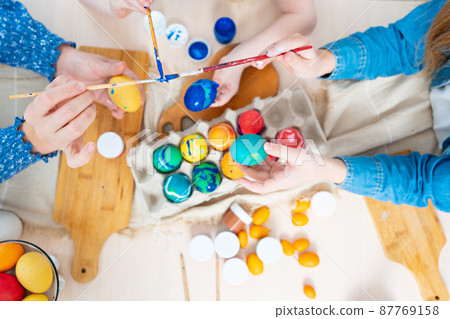 top view. hands of mom and daughters decorate Easter eggs with paints. top view. hands of mom and daughters decorate Easter eggs with paints. 87769158