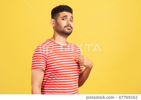 Egocentric selfish man pointing finger at himself, looking with pride and arrogance, feeling self-important and famous. Indoor studio shot isolated on yellow background 87769162