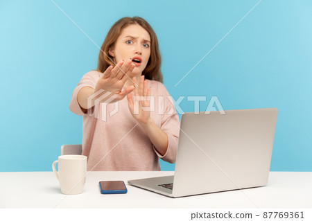 No, I'm scared. Frightened woman with shocked expression raising hands in stop gesture, defending herself, freaked out of troubles while working on laptop from home office. indoor studio shot isolated 87769361