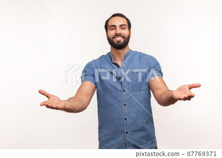 Open hearted generous man with beard sharing opening hands looking at camera with kind smile, greeting and regaling, happy glad to see you. Indoor studio shot isolated on white background 87769371