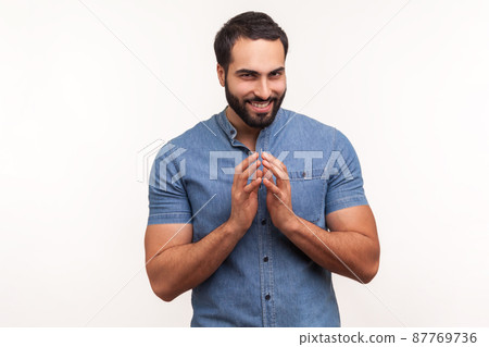 Cunful sneaky man in blue shirt gesticulating with fingers planning devious tricks and cheats, scheming prank, having fun. Indoor studio shot isolated on white background Cunful sneaky man in blue shirt gesticulating with fingers planning devious tricks and cheats, scheming prank, having fun. Indoor studio shot isolated on white background 87769736