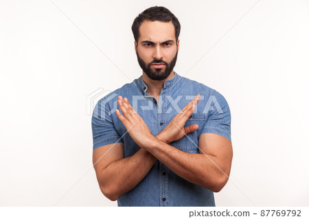 There is no way. Strict bossy bearded man in blue shirt showing x gesture with hands, rejection sign, warning about wrong way. Indoor studio shot isolated on white background There is no way. Strict bossy bearded man in blue shirt showing x gesture with hands, rejection sign, warning about wrong way. Indoor studio shot isolated on white background 87769792