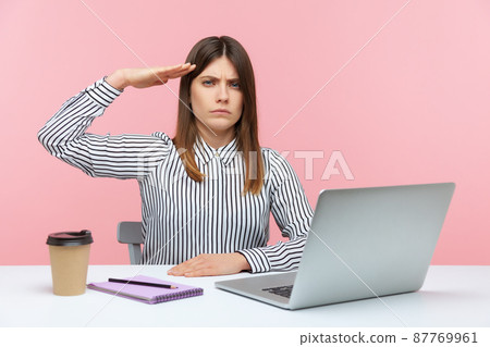 Yes sir. Obedient responsible business woman sitting at workplace with laptop and saluting, listening to boss order, corporate discipline. Indoor studio shot isolated on pink background Yes sir. Obedient responsible business woman sitting at workplace with laptop and saluting, listening to boss order, corporate discipline. Indoor studio shot isolated on pink background 87769961