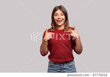 Wow, this is me. Portrait of amazed brunette girl in shaggy sweater pointing herself, looking at camera with shocked surprised expression, happy and proud of own achieved goal. studio shot isolated 87770016
