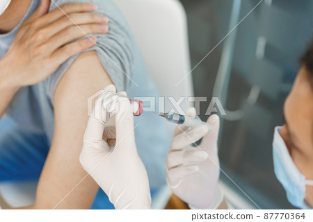 Vaccination concept, Male doctor preparing vaccine against covid-19 to injecting for male patient Vaccination concept, Male doctor preparing vaccine against covid-19 to injecting for male patient 87770364