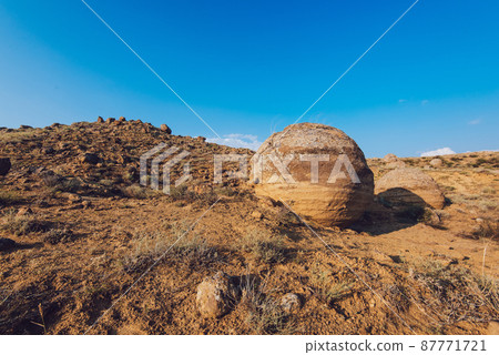 Round boulder in sandy area on summer day 87771721