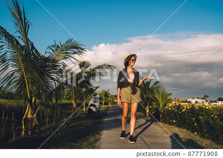 Smiling blogger with mobile phone strolling 87771908