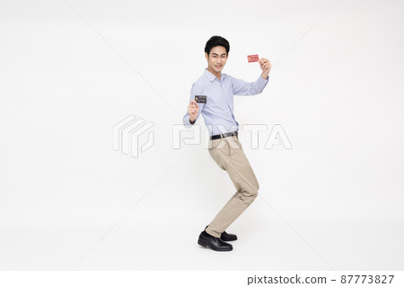 Young Asian man smiling, showing, presenting credit card for making payment or paying online business standing isolated on white background 87773827