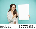 Asian business woman showing and holding blank white billboard isolated on green background 87773981