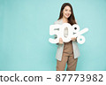 Portrait of Asian business woman showing and holding 50% number or Fifty percent isolated over light green background 87773982