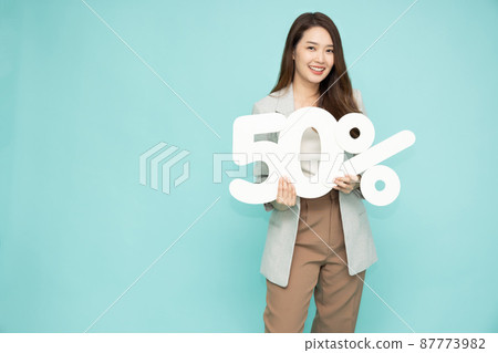 Portrait of Asian business woman showing and holding 50% number or Fifty percent isolated over light green background Portrait of Asian business woman showing and holding 50% number or Fifty percent isolated over light green background 87773982