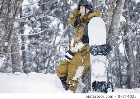 Snowboard girls standing in a snowy ski resort Snowboard girls standing in a snowy ski resort 87774025
