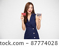 Young beautiful Asian woman smiling, showing, presenting credit card for making payment or paying online business, Pay a merchant or as a cash advance for goods, Cardholder or A person who owns a card 87774028