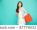 Asian business woman holding red shopping bags with Chinese new year festival isolated on green background 87774032
