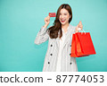 Asian business woman holding credit card and red shopping bags with Chinese new year festival isolated on green background 87774053