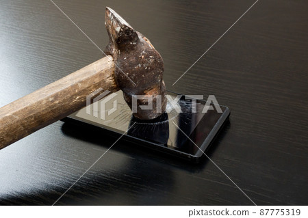 Hammer smashes the phone on wooden table 87775319