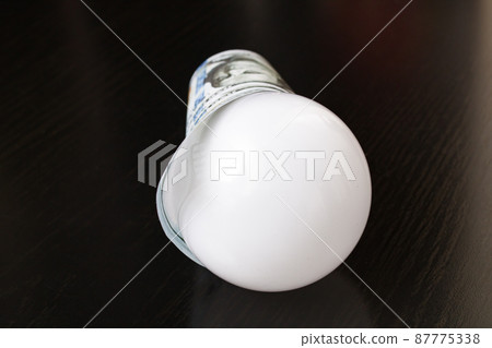 Light bulb wrapped in dollars on wooden table Light bulb wrapped in dollars on wooden table 87775338