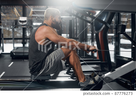 A man trains his arms and chest in the gym on the simulator, does exercises for different muscle groups. Fintes motivation, sports lifestyle, health, athletic body, body positive. Film grain. 87776273