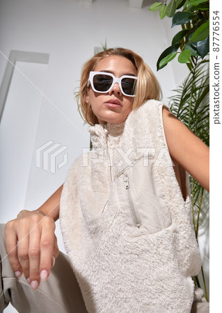 Beautiful woman close up portrait in faux fur vest with sunglasses. White fur coat. Elegant hair style. Dreamy face model 87776554