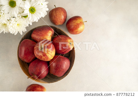 Red apples in bowl on wooden rustic background. Fresh red apple fruits with flowers, top view Red apples in bowl on wooden rustic background. Fresh red apple fruits with flowers, top view 87778212