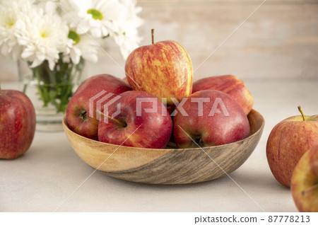 Red apples in bowl on wooden rustic background. Fresh red apple fruits with flowers. 87778213