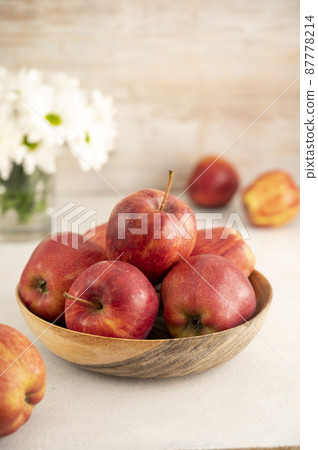 Red apples in bowl on wooden rustic background. Fresh red apple fruits with flowers. 87778214