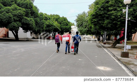 Three people are walking along the road 87778684