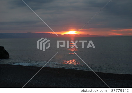 雲與山之間看到的橙色晨光，太陽在海面上的路徑，海的岸邊和白浪，沙灘和岩石區的風景 87779142