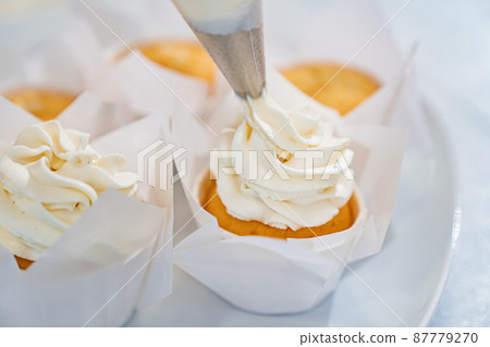 close-up. cupcakes are decorated with white cream from a cooking bag.  87779270