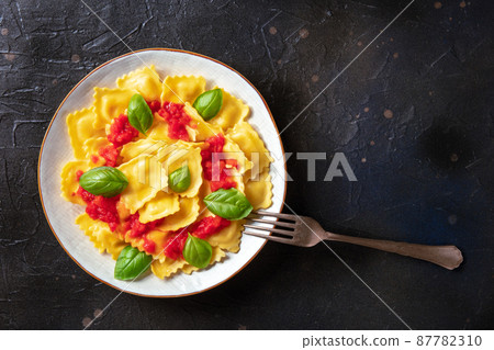 Ravioli with tomato sauce and basil on a plate, top shot with a fork 87782310