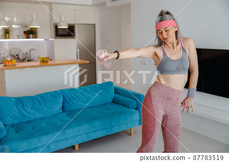 Sporty woman having morning workout in living room 87783519