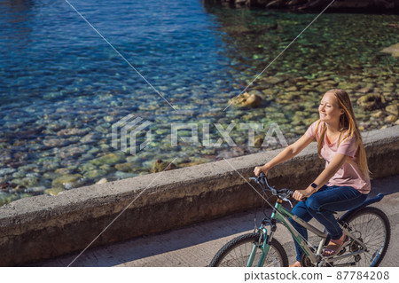 Woman tourist on a bicycle explores Budva in Montenegro. Cycling in Montenegro concept 87784208