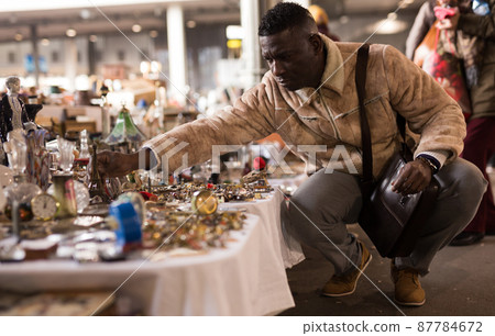 ordinary Afro-American guy considers things sacond hands on flea market 87784672