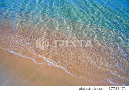 Seascape with surface of blue sea water with small ripple waves crashing on yellow sandy beach. Travel and vacations concept. Seascape with surface of blue sea water with small ripple waves crashing on yellow sandy beach. Travel and vacations concept. 87785471