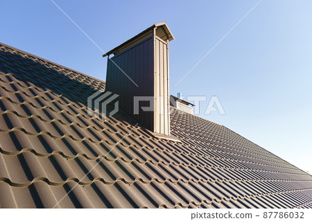 Chimney on house roof top covered with metallic shingles under construction. Tiled covering of building. Real estate development 87786032