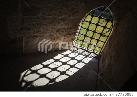 Locked window in dark ancient prison interior Locked window in dark ancient prison interior 87786095