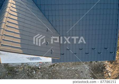 Aerial view of unfinished house with aerated lightweight concrete walls and wooden roof frame covered with metallic tiles under construction. 87786151