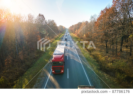 Aerial view of semi-truck with cargo trailer driving on highway hauling goods in evening. Delivery transportation and logistics concept 87786176