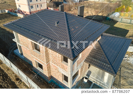Aerial view of house roof top covered with ceramic shingles. Tiled covering of building under construction 87786207