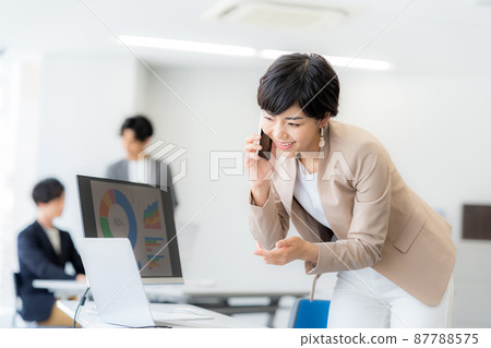 有一部智能手機的女商人在辦公室 有一部智能手機的女商人在辦公室 87788575