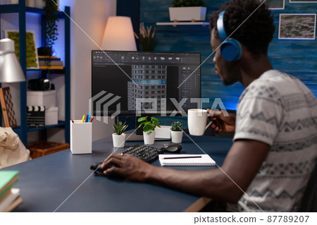 Young architect wearing headphones looking at building structure 87789207