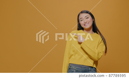 Positive adult pointing at left side of studio in front of camera Positive adult pointing at left side of studio in front of camera 87789395